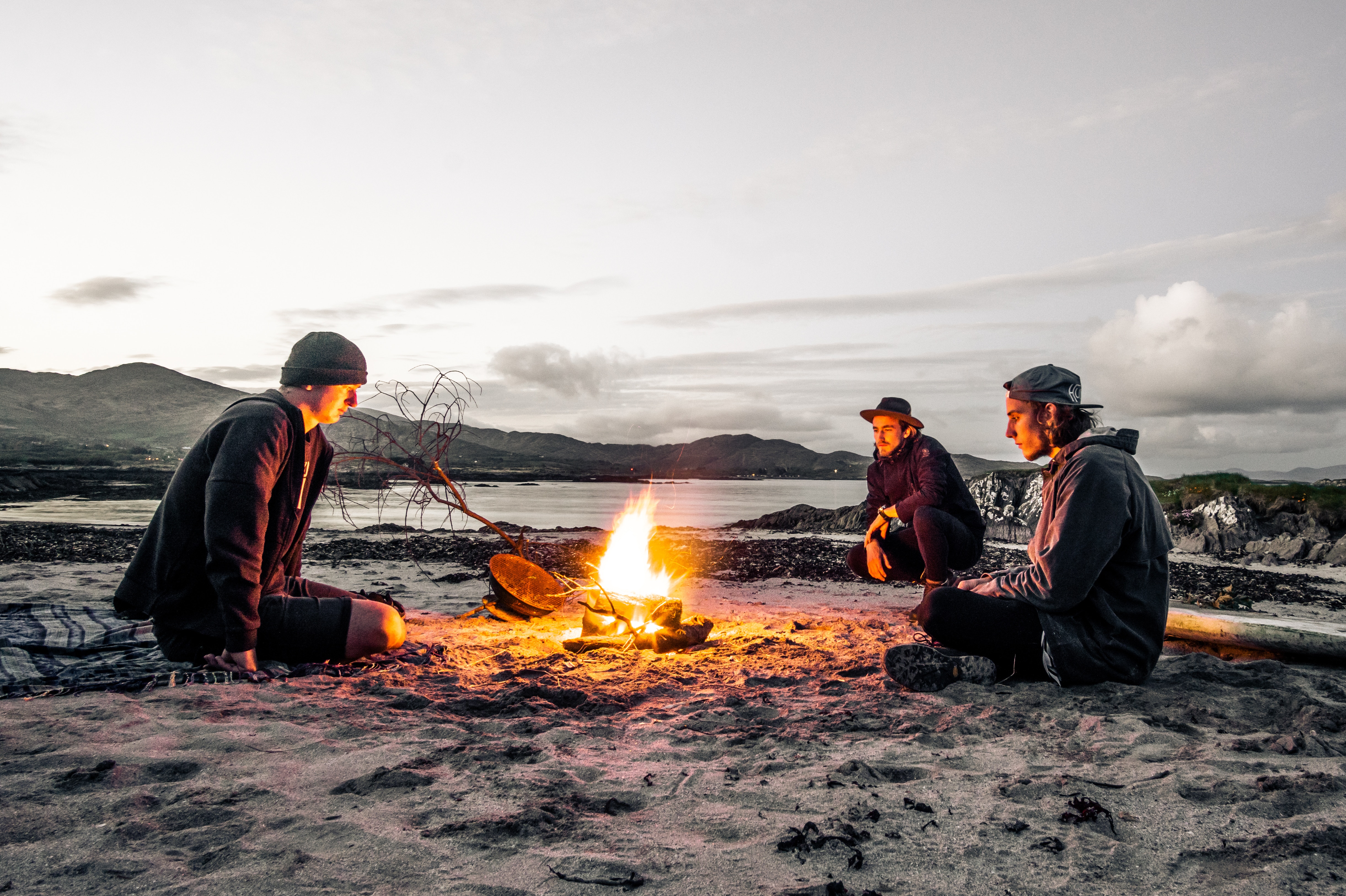 Friends around a fire on the beach at dusk